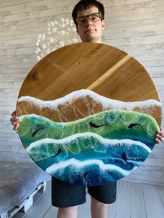 a man holding up a large wooden plate with seagulls flying over the waves