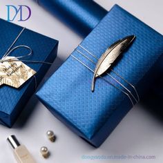 a blue gift box with a feather on it and a tag tied to the side