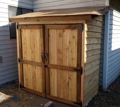 a wooden storage shed sitting next to a house