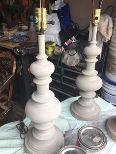 two white candlesticks sitting next to each other on a table with cans in the background