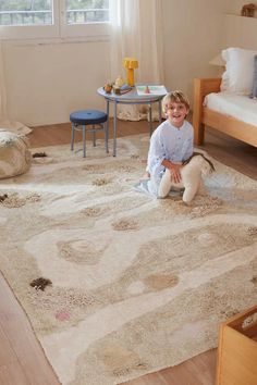 a little boy sitting on the floor in front of a rug