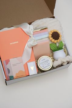 an open box filled with assorted items on top of a white table next to a plant