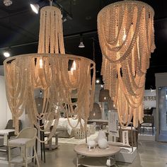 several chandeliers hanging from the ceiling in a room with tables and chairs around them