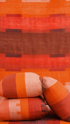 three pillows stacked on top of each other in front of an orange and brown striped wall