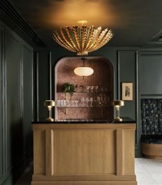 an elegant bar in the middle of a room with dark green walls and gold accents