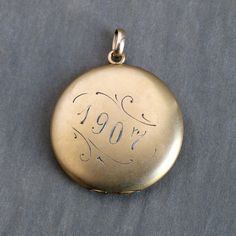 An antique Edwardian yellow gold-filled locket engraved with an ornate foliate-style monogram on the front "K.R.C." and dated 1907 on the back. The letters have richly oxidized over the years, the dark patina is striking against the soft glow of the metal. The locket measures approximately 1 3/8" in diameter. It opens to reveal space for two photos. In excellent condition with a light antique patina. Opens and closes firmly with a solid "snap!" RETURNS & EXCHANGES: Items may be returned for any reason as long as they are in their original condition, although resizing, engraving or alteration of any kind, done by us or another jeweler, makes the item a final sale. A 5% restocking fee will apply to the refund of the original purchase price; shipping charges, if applicable, are non-refundable Antique Etched Pendant Locket Necklace, Antique Etched Medallion Locket Necklace, Antique Engraved Oval Locket Necklace, Antique Etched Oval Locket Necklace, Antique Etched Yellow Gold Locket Necklace, K R, Custom Gift Boxes, R C, Style Expert