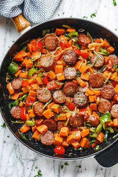 a skillet filled with sausage and vegetables