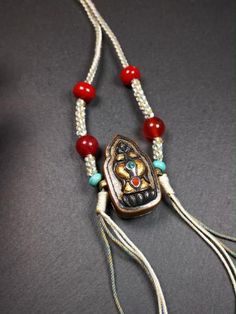 a necklace with red beads and an animal head on it