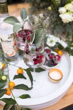 two wine glasses filled with cranberries and greenery sit on a white tray