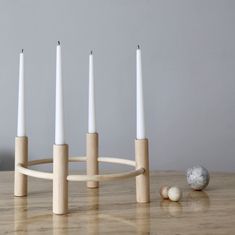 four candles are placed in front of each other on a wooden stand with marble balls