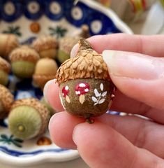 a hand is holding a tiny figurine in front of some nuts on a plate