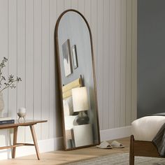 a large mirror sitting on top of a wooden floor next to a table and chair