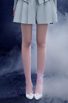 a woman in short shorts and heels standing on a foggy surface with her hands behind her back