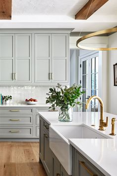 a large kitchen with white cabinets and gold handles on the countertops, along with an island in the middle