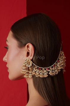 a woman with long hair wearing a gold and red head piece, earrings and necklace