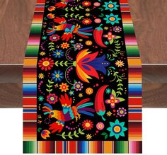 a table runner with colorful flowers and birds on black fabric, along with multi - colored stripes