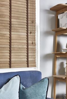 a blue couch sitting in front of a window with wooden blinds