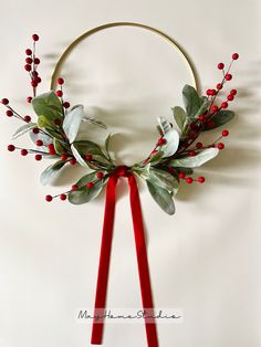 a wreath with red berries and greenery on it is hanging from a metal hoop