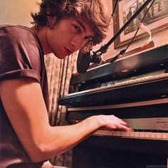 a young man is playing the piano in his living room