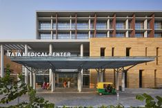 the entrance to a medical center with people walking around it and cars parked in front