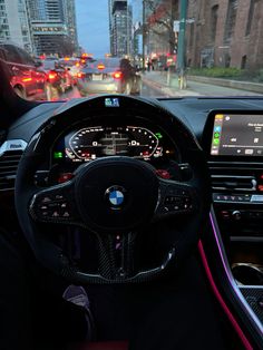 the interior of a bmw car on a city street with traffic lights and buildings in the background