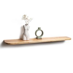 a white vase with flowers on a wooden shelf next to a ceramic ring and flower pot