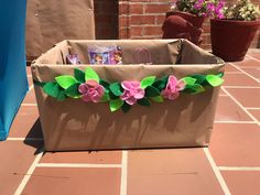 a brown paper bag with pink flowers and green leaves on the inside is sitting on a tile floor