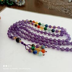 Handmade/Handcrafted ｡.｡  ｡.｡ Number of beads: 108 Beads Guru bead  Size of 10MM  Mala Bead Size: 8 mm Tassel height: 3 Inches ｡.｡  ｡.｡ »»--------><--------«« IF worn on your neck as a  necklace, it will have a length of around 45 cm / 18 inches; the length of the whole mala is around 95 cm / 38 inches.Chakra Colors Let's look at the 7 Chakra colors: 1- RED - The Root Chakra 2- ORANGE - The Navel or Sacral Chakra 3- YELLOW - The Solar Plexus Chakra 4- GREEN - The Heart Chakra 5- BLUE - The Throat Chakra 6- INDIGO - The Third Eye Chakra 7- VIOLET - The Crown Chakra This necklace measures  approx 21 Inches 54 cm Bids size - 8mm approx 108 Beads/  Natural Amethyst Seven Chakra Japa Mala Prayer Beads Blue colour Round Beads Japa Mala Guru bead Necklace semi-precious Gemstone Round Beads // Lon Round Gemstone Beads For Meditation, Handmade Round Crystals For Meditation, Amethyst Gemstone Beads, Gemstone Beads Mala As Gift, Gemstone Beaded Necklace For Meditation, Handmade Purple Spiritual Beaded Necklaces, Handmade Purple Beaded Necklaces With Spiritual Style, Spiritual Round Gemstone Beaded Necklaces, Adjustable Amethyst Round Bead Crystals