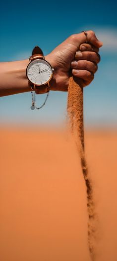 a person holding onto a sand clock in the desert