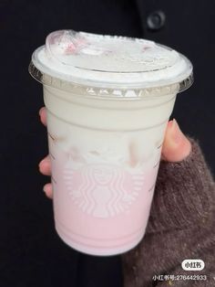 a person holding up a starbucks cup with pink liquid in it's sleeve and brown cardigan sweater