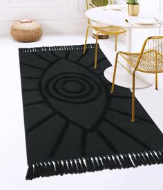 a black rug with tassels on it in a white room next to a chair