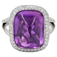 Introducing the epitome of regal elegance, behold the breathtaking 15.83-carat Sugarloaf Cabochon Purple Sapphire Diamond Ring, meticulously crafted by Spectra Fine Jewelry in 2022. This magnificent piece features a mesmerizing purple sapphire of Ceylon origin, boasting its natural beauty with no signs of heating, certified by GRS. The center stone is embraced by a dazzling halo of pave diamonds, extending gracefully onto the band, adding an extra touch of brilliance and sophistication. Encased in platinum, with a total weight of 8.95 grams, this ring exudes luxury and refinement. Sized at 6, with the option for resizing, it's a timeless treasure destined to captivate hearts and steal the spotlight on any occasion. Luxury Purple Platinum Jewelry, Luxury Purple Jewelry With Brilliant Cut, Luxury Purple Sapphire Fine Jewelry Ring, Purple Sapphire Jewelry With Brilliant Cut, Luxury Purple Diamond-cut Jewelry, Regal Elegance, Purple Sapphire, Sapphire Diamond Ring, Gem Stone