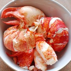 a bowl filled with cooked lobsters on top of a table