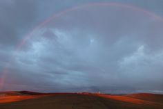 two rainbows are in the sky over a field