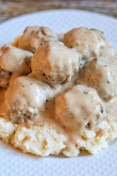 a white plate topped with biscuits and gravy covered in sauce on top of mashed potatoes