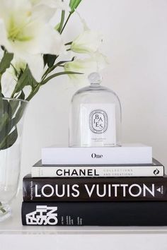 three books stacked on top of each other next to a vase with flowers