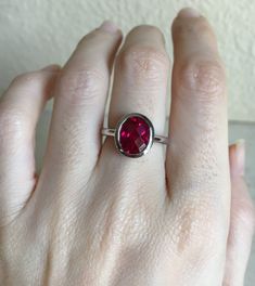 "A Classic oval shaped Faceted Lab Created Ruby Sterling Silver Ring featuring a comfort fit band with a bezel around the stone. This makes a great birthstone ring for those July Birthdays! Wrapped in a box ready for gift giving.(r-537) RING INFO ---------------- STERLING SILVER Stone with Bezel measure 11.5mm x 10mm July BIRTHSTONE *Follow us @belesasjewelry on Instagram for promotions/giveaways *LIKE* us on Facebook http://www.facebook.com/Belesas *If you like the ring, please click on the \"P Classic Red Ring With Bezel Setting, Classic Red Rings With Bezel Setting, Classic Red Bezel Set Ring, Modern Ruby Ring With Bezel Setting, Classic Adjustable Red Ring, Adjustable Oval Red Ring, Adjustable Red Oval Ring, Red Promise Ring With Bezel Setting, Adjustable Red Oval Ruby Ring