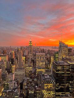 the city skyline is lit up at night with bright oranges and yellows in the sky