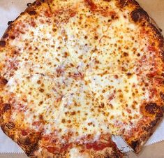 a cheese pizza sitting on top of a white piece of paper next to a knife