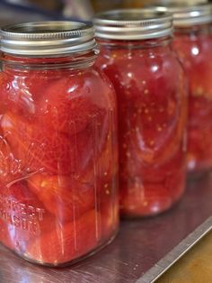 several jars filled with pickled tomatoes on top of a table