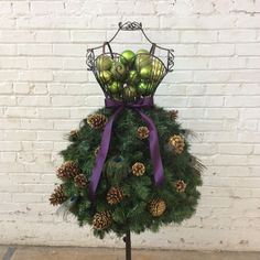 a christmas tree with balls and pine cones on it in front of a brick wall