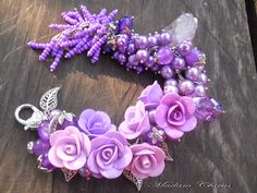 purple flowers and pearls are arranged on a wooden table