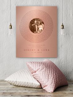 a pink pillow on top of a wooden table next to a wall mounted poster with an image of two people