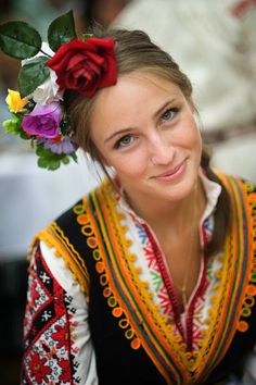 a woman with flowers in her hair and a flower in her hair is smiling at the camera