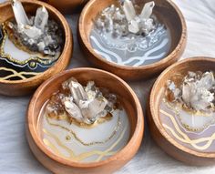 four wooden bowls filled with different types of crystals