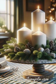 three white candles are on top of a cake plate with pine cones and evergreen branches