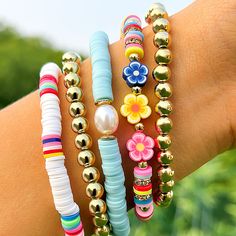 a person's arm with several bracelets on it, including beads and flowers