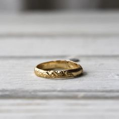 a gold wedding ring sitting on top of a wooden table