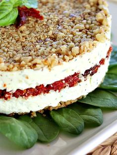 a close up of a cake on a plate with green leaves and strawberries in the background