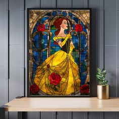 the beauty and the beast stained glass art is displayed on a shelf next to a potted plant